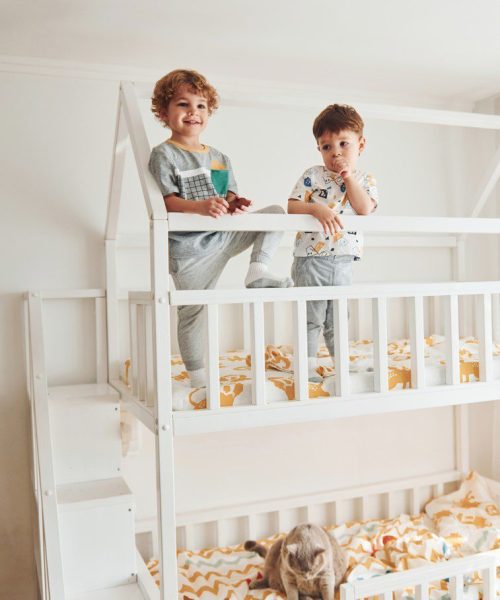 Two little boys resting and have fun indoors in the bedroom together.